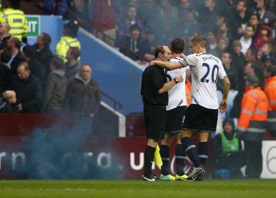 West Midlands police have arrested two men after a linesman was struck on the back of the neck by a flare during Tottenham Hotspur’s 2-0 win at Aston Villa.