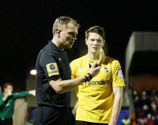 A 74-year-old pensioner has been arrested after allegedly throwing a banana at referee Graham Scott during AFC Wimbledon's game with Port Vale.